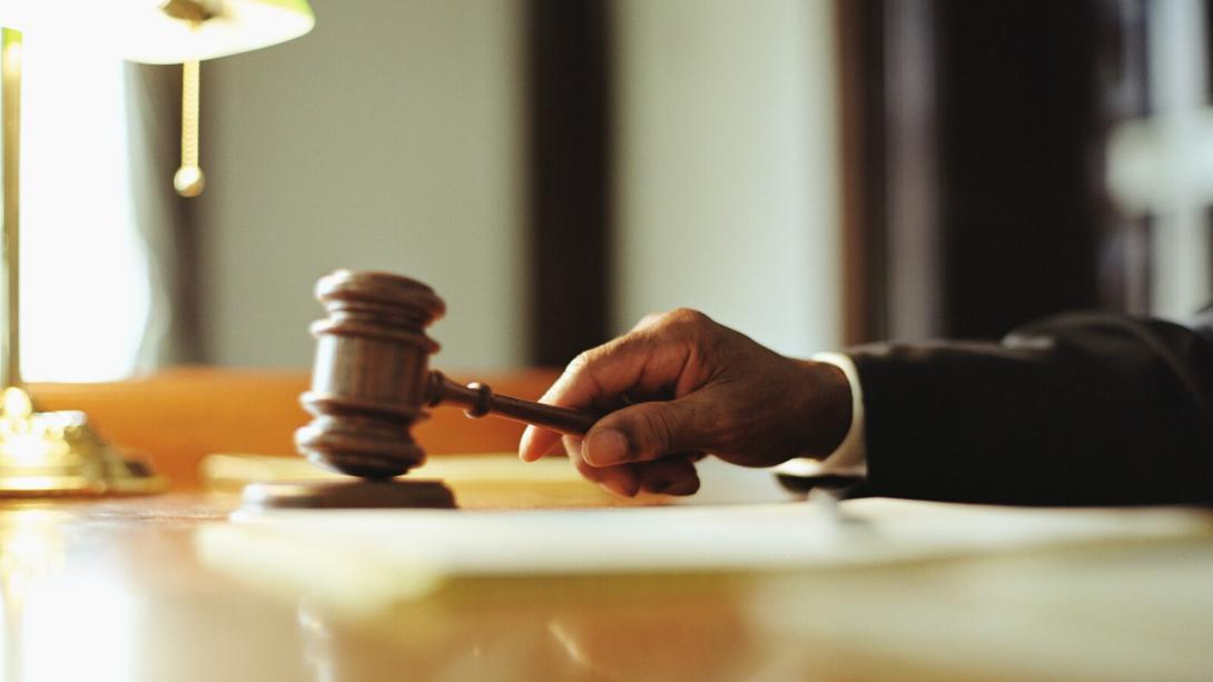 Gavel in judges hand at desk