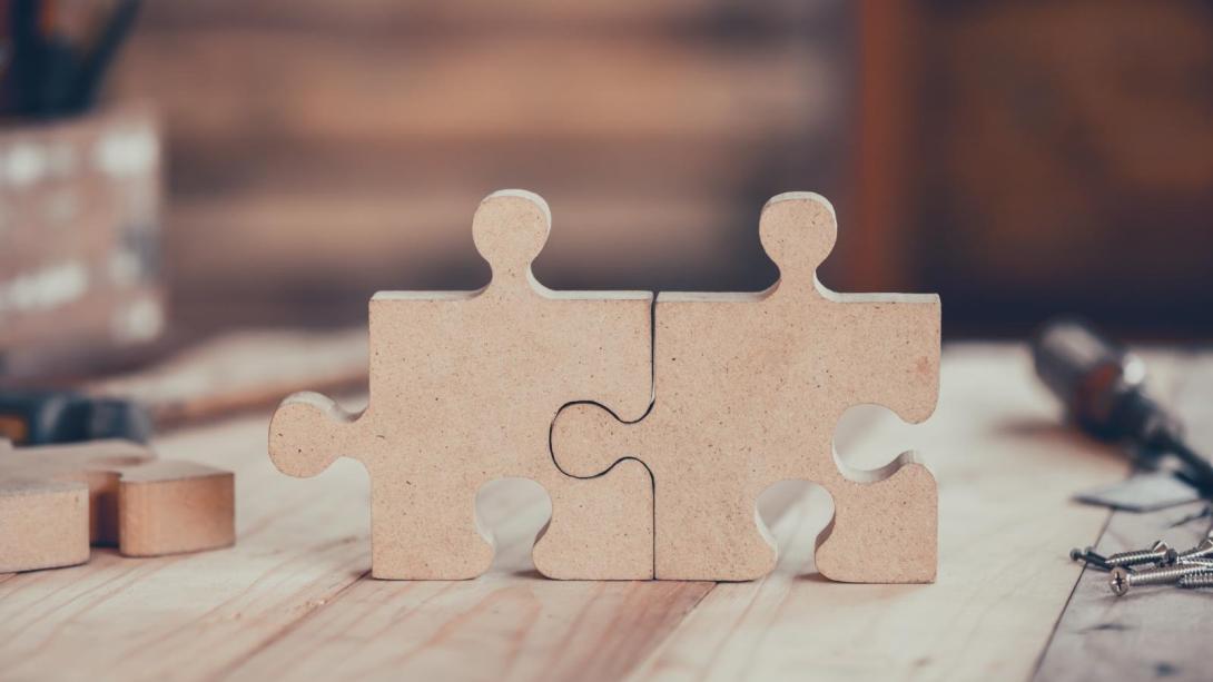 Two puzzle pieces joined together sitting on a woodworking table