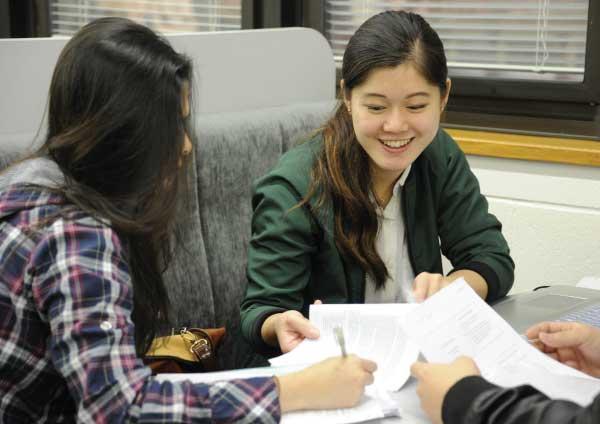 Students looking at documents in a library.