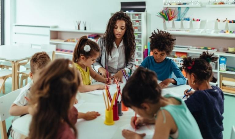 Early Childhood Education and Care (ECEC) teacher and students colouring at a table in a classroom