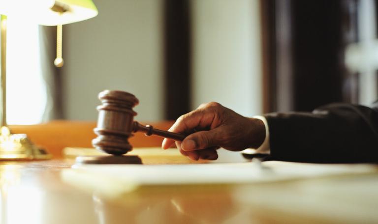 Gavel in judges hand at desk