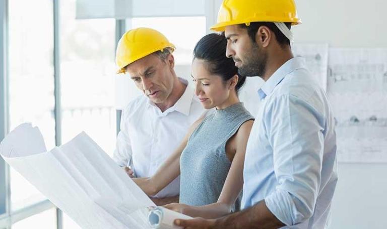 Female and male in construction looking at a building plan in an office environment