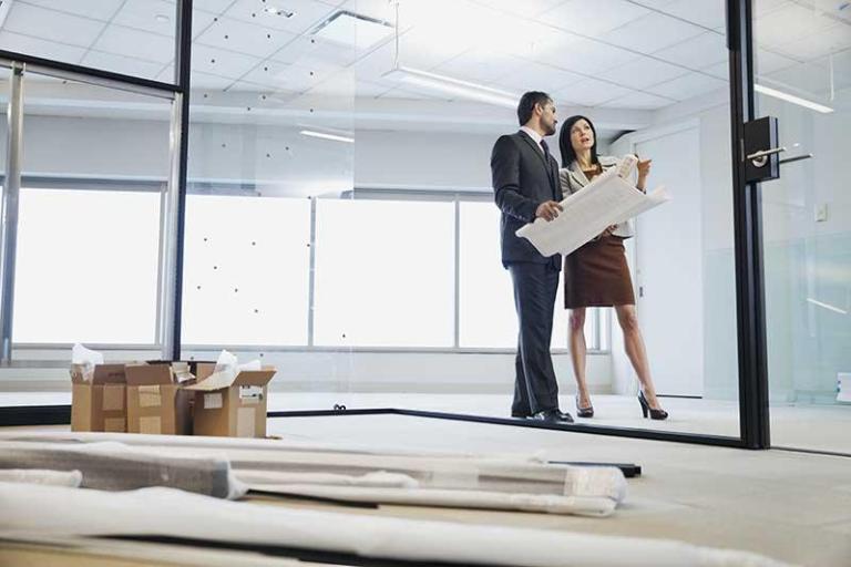 Two real estate agents looking at construction map and planning the property management