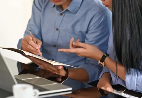 Two colleagues looking at papers sitting at a desk