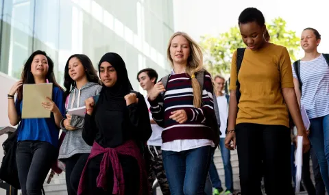 Group of students with backpacks smiling, talking and walking with books