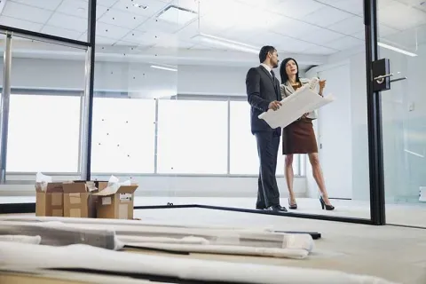 Two real estate agents looking at construction map and planning the property management