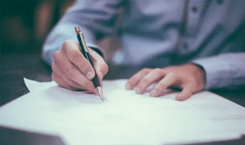 Man's hands signing document